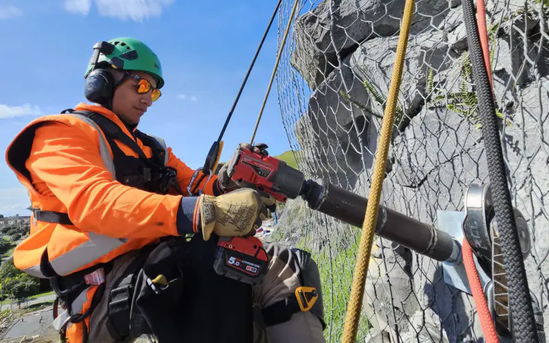 Geo Mana rope-access technician working on an anchored rock face
