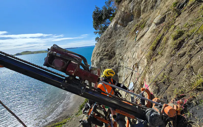 Geo Mana drilling crew installing ground support on a steep coastal workface